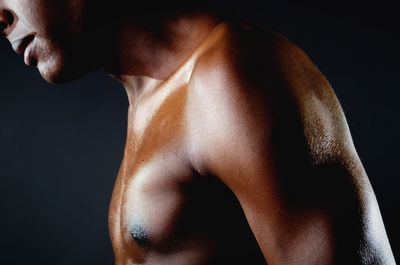 Close-up of shirtless man against black background