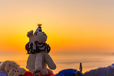 Close-up of stuffed toy against sky during sunset