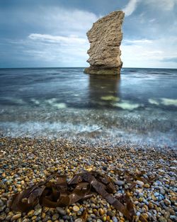 Rocks on shore at beach against sky