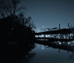 Bridge over river in city against clear sky at night