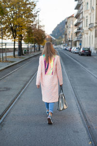 Rear view of woman walking on road in city