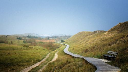 Road leading towards mountain against clear sky