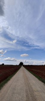 Road amidst field against sky