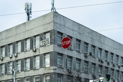 Low angle view of road sign by building against sky