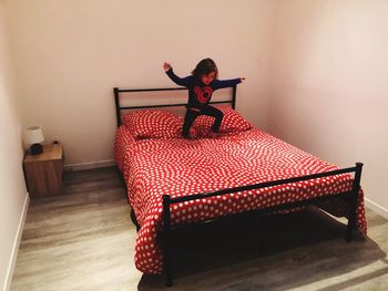 Cute girl jumping on bed at home