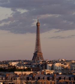 Tower and buildings in city against cloudy sky