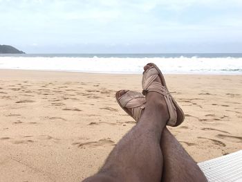 Low section of man relaxing on beach