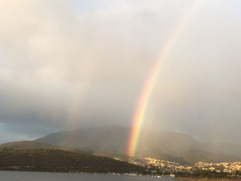 Scenic view of rainbow over mountains against sky