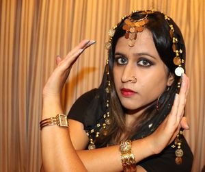 Close-up portrait of beautiful woman wearing jewelry dancing against wall