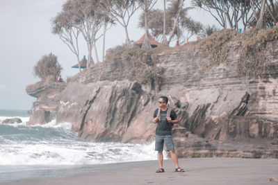 Full length of man standing on rock at beach