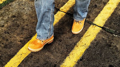 Low section view of man walking between yellow lines