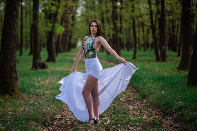 Portrait of woman with umbrella on field in forest