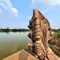 Statue by lake against sky