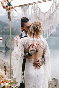 A loving married couple the bride and groom in suits celebrate wedding near the mountains and water