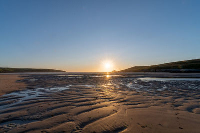 Landscape photo of the sun setting over crantock beach in cornwall