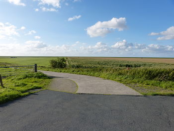 Road amidst field against sky