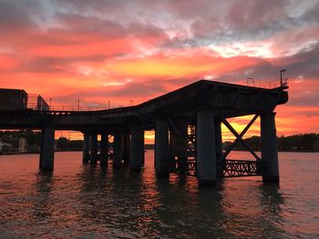 Bridge over river against orange sky