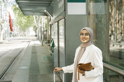 Beautiful woman holding purse while standing at station