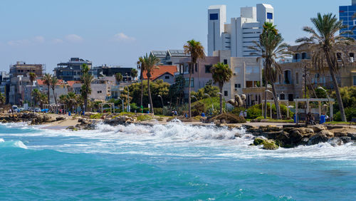 Buildings by sea against sky