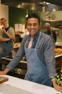 Portrait of happy mature male student standing in kitchen during cooking class