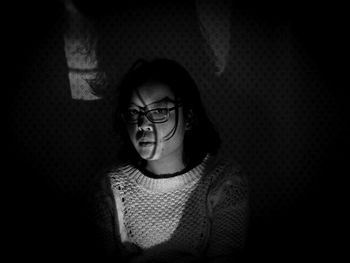 Portrait of woman wearing eyeglasses in darkroom