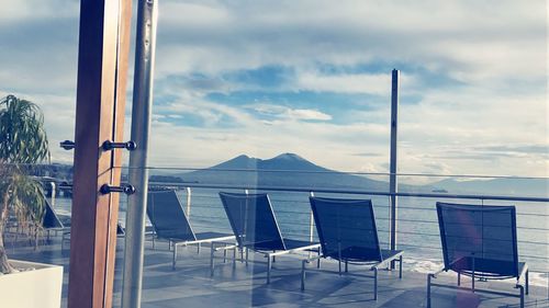 Chairs on beach by sea against sky