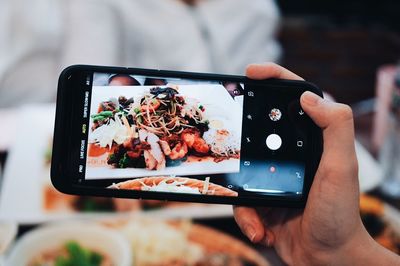 Midsection of person photographing food with mobile phone