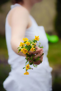 Close-up of woman holding yellow flowering plant