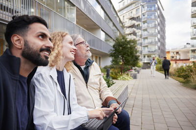 Men and woman with laptop looking at buildings