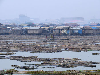 Huts at dirty beach against sky