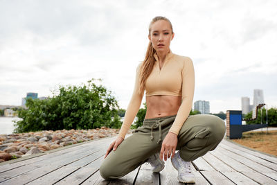 Portrait of young woman sitting on wooden wall