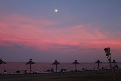 Scenic view of beach with sunbeds at twilight