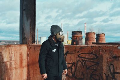 Worker in gas mask standing against wall