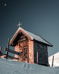 Low angle view of house on snow covered field against sky