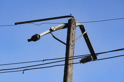 Low angle view of telephone pole against clear blue sky