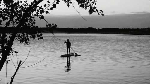 Silhouette man fishing in lake against sky