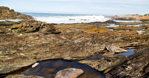 Scenic view of rocks on beach against sky