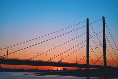 Silhouette bridge over river against sky during sunset