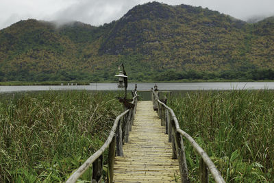 Jetty leading towards lake against mountains