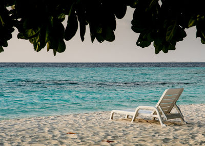 Chairs on beach against sky