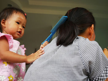 Girl combing mother hair at home