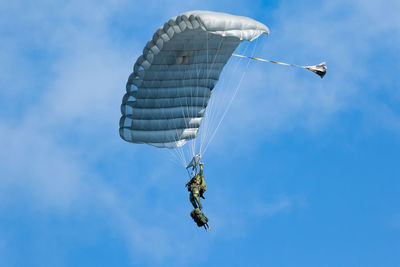 Low angle view of man paragliding against sky