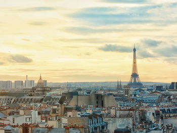 Eiffel tower amidst cityscape against sky during sunset