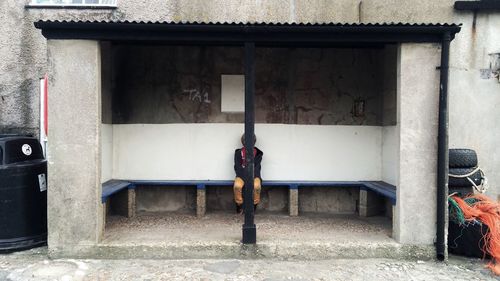 Boy sitting behind pole