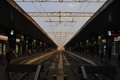 People at railroad station against sky