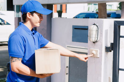 Salesman ringing doorbell while standing at gate way