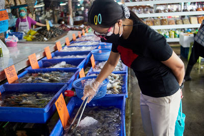 Woman's hand putting on plastic glove and holding serving tongs for picking lobster