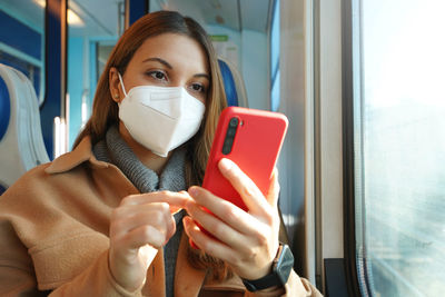Safety on public transport. young woman with ffp2 kn95 face mask using mobile phone on train.