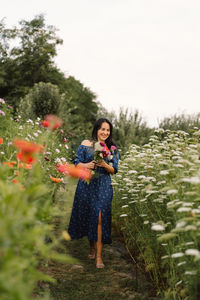 A young woman walks with a bouquet of flowers in a floristic flower farm.