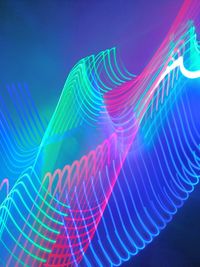 Low angle view of light trails against blue sky at night